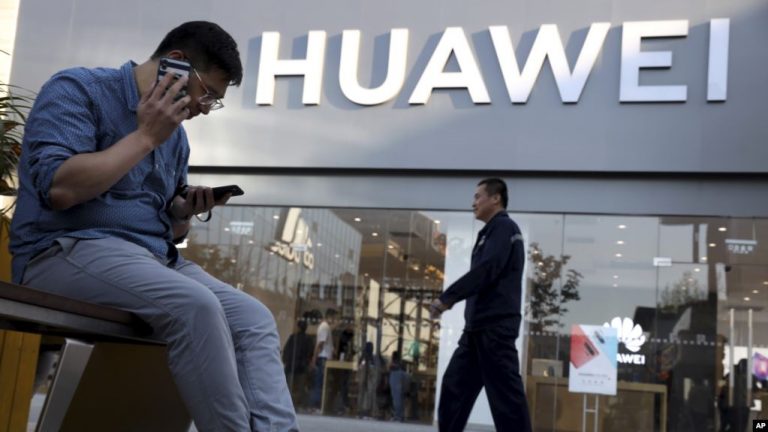 Sử dụng điện thoại thông minh bên ngoài một cửa hiệu Huawei ở Bắc Kinh, 20 tháng Năm, 2019. Ảnh: VOA