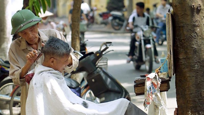Người thợ hớt tóc cao tuổi vẫn còn làm việc tại Hà Nội, ảnh chụp trước đây. Ảnh: AFP
