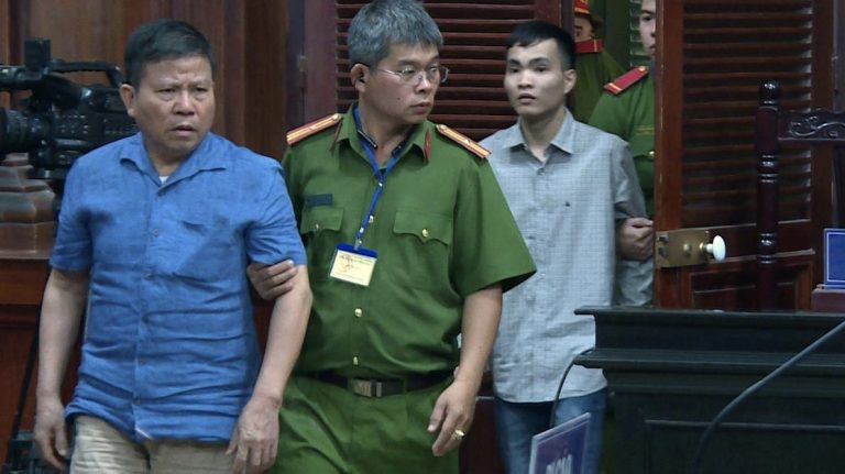 Ông Châu Văn Khảm (áo xanh) trong phiên tòa sơ thẩm. Ảnh: AP