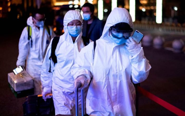 Hành khách mặc đồ bảo hộ toàn thân chống chất độc hại (Hazmat suit) khi đến ga xe lửa Wuhan Wuchang ở Vũ Hán để rời khỏi thành phố nầy rạng sáng 8/4/2020, ngay sau khi lệnh phong tỏa thành phố được gỡ bỏ. Ảnh: AFP