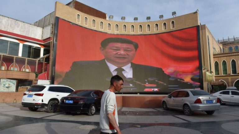 Một người đàn ông đi ngang qua một màn ảnh to có hình của Chủ Tịch Cộng Sản Trung Quốc Tập Cận Bình tại Kashgar, Tây Bắc Tân Cương hôm 4/6/2019. Ảnh: Greg Baker /AFP