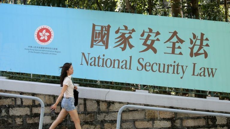 Một phụ nữ đi qua một bảng cổ động Luật An Ninh Quốc Gia phiên bản Hong Kong. Ảnh chụp hôm 30/6/2020, cùng ngày Trung Quốc đã phê chuẩn đạo luật nầy, gây ra lo ngại rằng nó sẽ được sử dụng để kiềm chế tiếng nói của phe đối lập và cư dân Hong Kong. Ảnh: AP/Kin Cheung