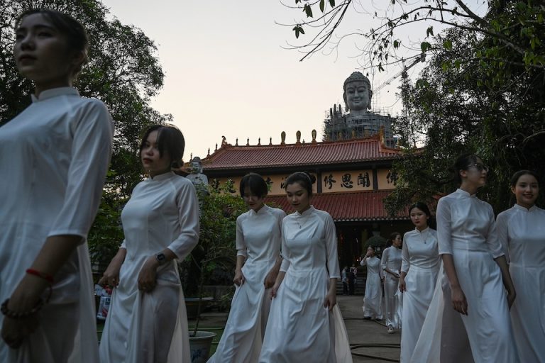 Hình minh hoạ. Các phụ nữ Việt Nam đi qua một tượng Phật tại chùa Khai Nguyên ở Sơn Tây, ngoại thành Hà Nội hôm 18/5/2019. Ảnh: AFP