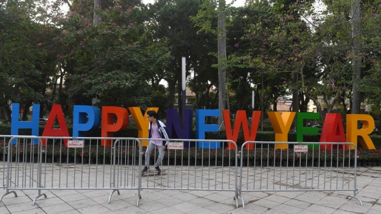 Một thanh niên đi ngang qua bảng hiệu "Chúc mừng Năm mới" ở Hà Nội. Hình chụp ngày 30/12/2020 (AFP)