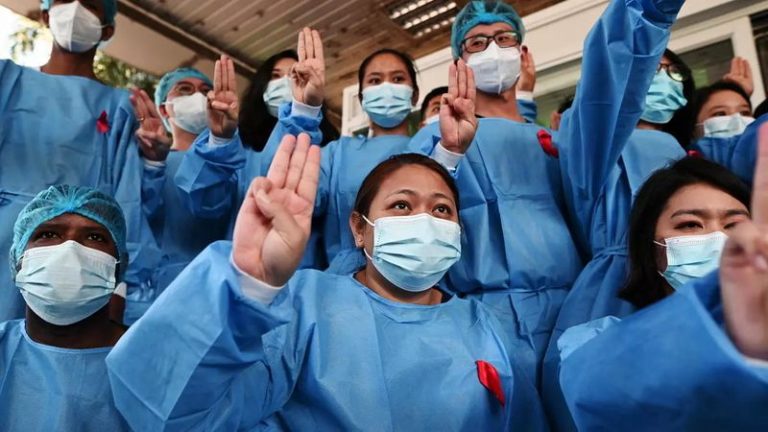 Nhân viên y tế cài ru-băng đỏ, giơ ba ngón tay, tiến hành đình công để phản đối cuộc đảo chính, tại bệnh viện Đa Khoa Rangoon, Miến Điện ngày 03/02/2021. Ảnh: Reuters