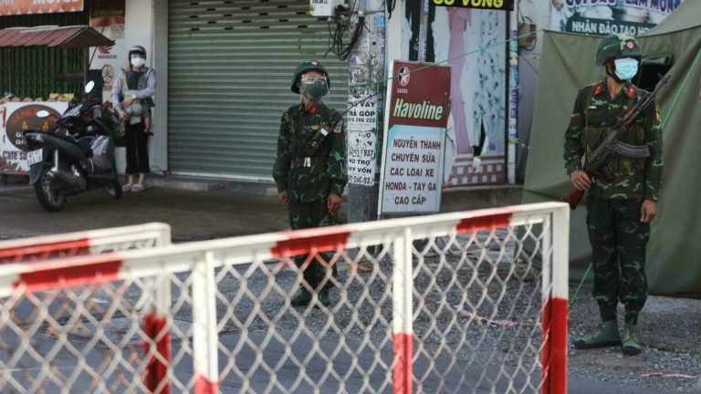 Quân nhân trang bị AK-47 canh gác một trạm kiểm soát trong ngày đầu tiên của đợt siết chặt phong tỏa "chống Covid" tại Sài Gòn, Việt Nam, ngày 23/08/2021. Ảnh: Reuters - Stringer