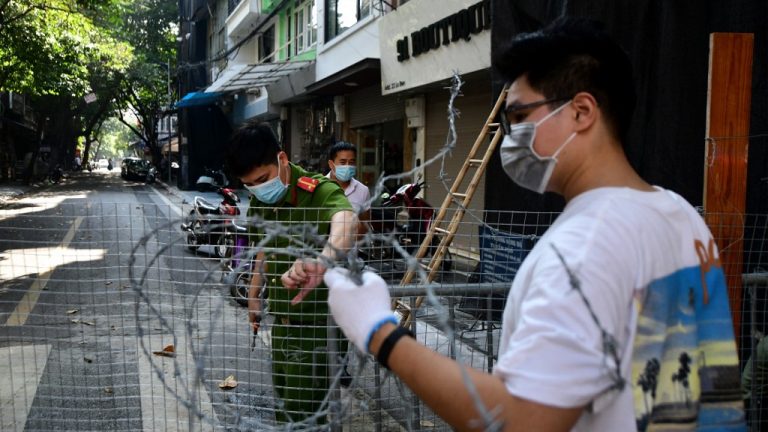 Công an dỡ bỏ rào chắn một con đường ở Hà Nội hôm 21/8/2021 sau 2 tháng 'giãn cách xã hội.' Ảnh: AFP
