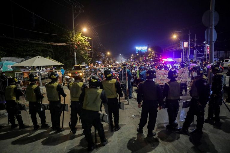 Công an, CSCĐ đứng chặn tại một chốt ở TP.HCM đêm 30/9/2021 khi người lao động bắt đầu rời thành phố trước khi lệnh phong tỏa được dỡ bỏ vào sáng hôm sau 1/10/2021. Ảnh: Reuters