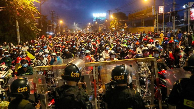 Dân "nhập cư" chờ tại một chốt chặn để bỏ Sài Gòn về quê khi lệnh phong tỏa về các quy định nghiêm ngặt do Covid-19 được áp dụng trong ba tháng qua bị hủy bỏ hôm 1/10/2021. Ảnh: Chi Pi/ AFP via Getty Images