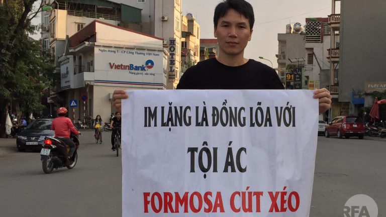 Ông Đỗ Nam Trung cầm băng rôn phản đối công ty Formosa gây ô nhiễm môi trường