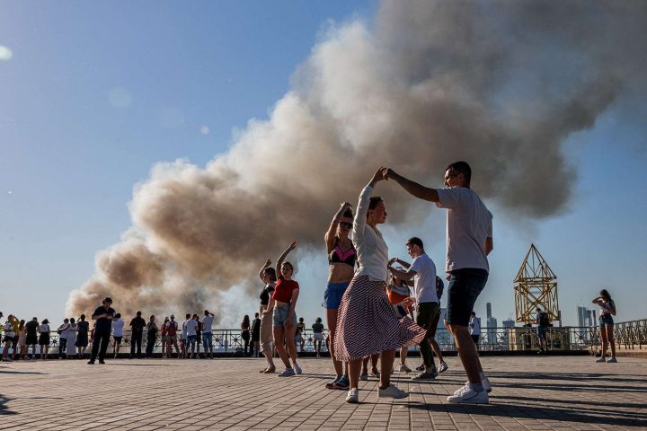 Các cặp đôi nhảy điệu Samba trong lúc khói bốc lên từ một kho pháo hoa đang cháy ở Moscow vào ngày 19/6/2021. Ảnh: DIMITAR DILKOFF/AFP VIA GETTY IMAGES