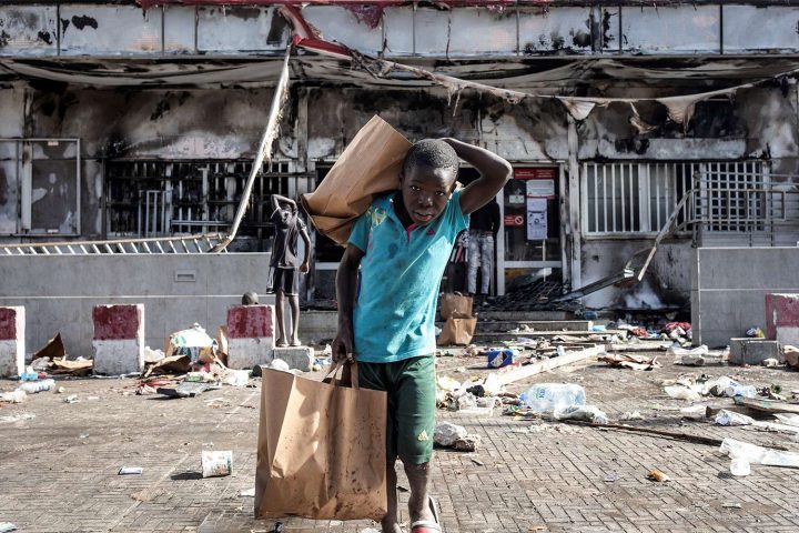 Một bé trai xách những túi đồ lấy được từ siêu thị Auchan sau khi bị đám đông cướp phá và đốt cháy ở Dakar, Senegal, vào ngày 6/3/2021. Sự kiện này xảy ra trong bối cảnh bùng phát những cuộc biểu tình bạo động phản đối việc bắt giữ nhà lãnh đạo đối lập Ousmane Sonko với cáo buộc hiếp dâm. Ảnh: JOHN WESSELS/AFP VIA GETTY IMAGES
