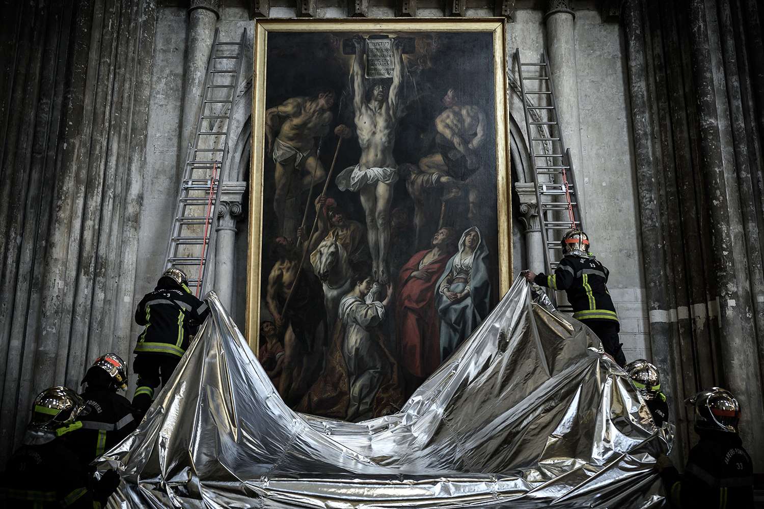 Lính cứu hỏa Pháp bảo vệ một bức tranh bằng chăn chống cháy trong cuộc diễn tập nhằm bảo quản các tác phẩm nghệ thuật trong nhà thờ Saint-Andre ở Bordeaux, Tây Nam Pháp, hôm 12/10/2021. Ảnh: PHILIPPE LOPEZ/AFP VIA GETTY IMAGES