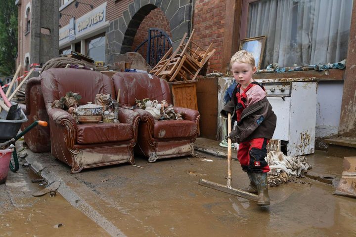 Một cậu bé trai đang giúp dọn dẹp bên ngoài ngôi nhà của mình sau trận mưa lớn và lũ lụt ở Rochefort, Bỉ, vào ngày 17/7/2021. Ảnh: JOHN THYS/AFP VIA GETTY IMAGES