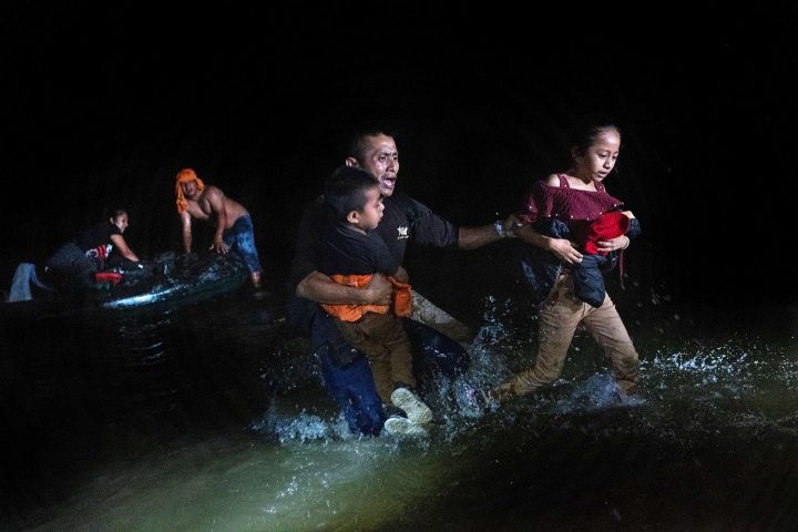 Một người cha nhập cư ôm chặt các con của mình khi đi băng qua sông Rio Grande ở biên giới Hoa Kỳ-Mexico ở Roma, Texas, vào ngày 14/4/2021. Ảnh: JOHN MOORE/GETTY IMAGES