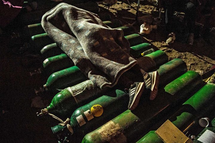 Một người ngủ trên những bình oxy rỗng trong lúc chờ được nạp lại bình ở Villa El Salvador, ngoại ô Nam Lima, Peru, vào ngày 25/2/2021. Thân nhân của nạn nhân COVID-19 đang rất cần oxy để giúp cho những người thân yêu của họ sống sót sau làn sóng dịch thứ hai. Ảnh: ERNESTO BENAVIDES/ AFP VIA GETTY IMAGES