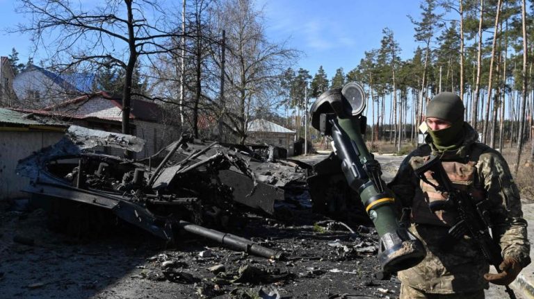 Một binh sĩ Ukraine trước xe tăng Nga bị phá hủy - nhờ vào vũ khí viện trợ của nước ngoài. Ảnh: AFP