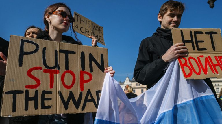 Các thành viên của cộng đồng người Nga ở nước ngoài tại Krakow, Ba Lan, hôm 20/3/2022 cầm biểu ngữ và hô khẩu hiệu phản đối cuộc xâm lược Ukraine của Tổng Thống Nga Vladimir Putin. Ảnh: Omar Marques/ Getty Images