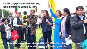 Cô Bùi Duyên, một thành viên Đảng Việt Tân phát biểu tại cuộc biểu tình. Ảnh chụp Youtube Việt Tân