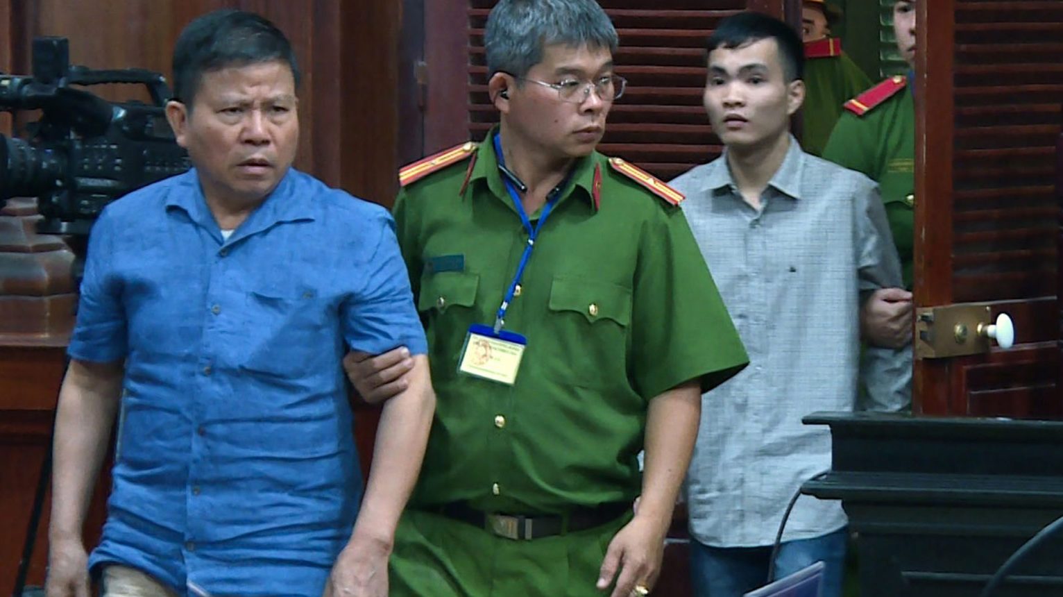 Ông Châu Văn Khảm (trái) bị dẫn giải ra tòa án CSVN ở Sài Gòn ngày 11/11/2019, và bị áp đặt 12 năm tù khi vu cho ông tội “khủng bố.” Ảnh: VNA/AFP/Getty Images