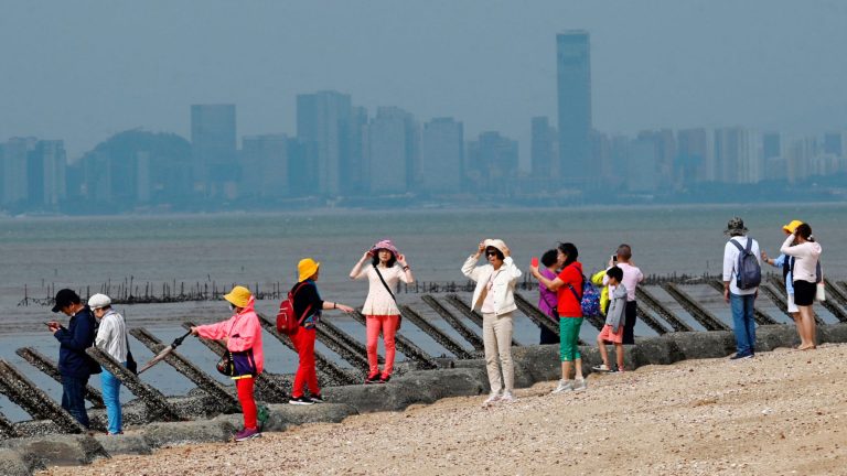 Du khách chụp hình bên các cột chống đổ bộ được đặt dọc theo bờ biển tại đảo Kim Môn của Đài Loan, chỉ cách bờ biển Trung Quốc Đại Lục 3,2 km ở eo biển Đài Loan. Đài Loan đang sống trong mối đe dọa thường xuyên của Trung Quốc. Ảnh: Sam Yeh/AFP via Getty Images