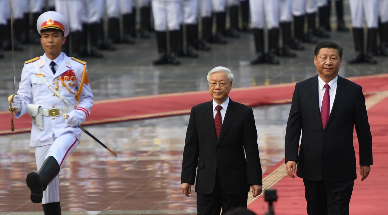 Ông Nguyễn Phú Trọng (giữa) cùng ông Tập Cận Bình (phải) bước trên thảm đỏ tại Phủ Chủ Tịch, Hà Nội, ngày 12/11/2017. Ảnh: Hoang Dinh Nam/ Pool/ AFP via Getty Images