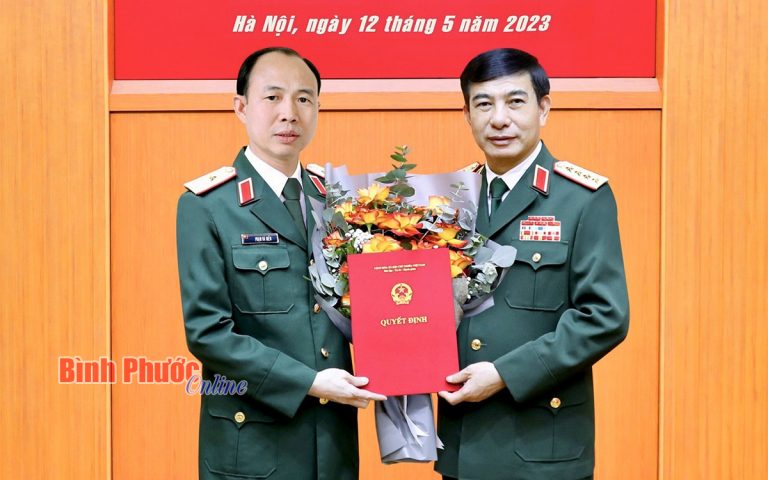 Đại tướng Phan Văn Giang (phải), Ủy viên Bộ Chính trị, Phó Bí thư Quân ủy Trung ương, Bộ trưởng Bộ Quốc phòng trao quyết định thăng quân hàm từ đại tá lên thiếu tướng và tặng hoa chúc mừng 'đồng chí' Phạm Bá Hiền. Ảnh: Bình Phước online