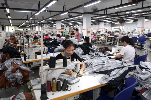 Công nhân đeo khẩu trang khi làm việc tại một nhà máy sản xuất quần áo bảo hộ lao động. Ảnh minh họa: RFA