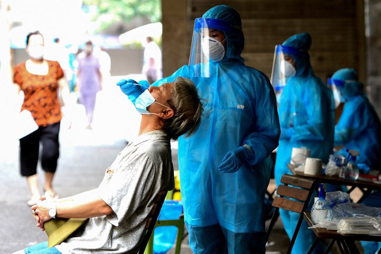 Một người dân đang được nhân viên y tế xét nghiệm corona virus tại chợ Đồng Xuân, Hà Nội vào ngày 11/8/2021, khi chính phủ áp đặt lệnh phong tỏa hai tuần. Ảnh: AFP