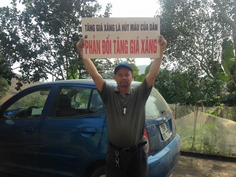 Ông Phan Vân Bách cầm tấm biển phản đối tăng giá xăng. Ảnh: Facebook/Phan Vân Bách