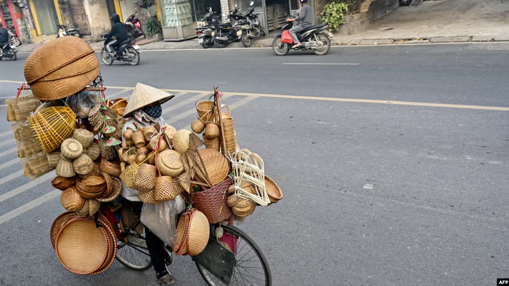Một phụ nữ bán hàng tre nứa trên đường phố Hà Nội. Phó Thủ tướng Việt Nam Lê Minh Khái hôm 20/5/2024 cho biết nền kinh tế Việt Nam đang đối mặt với áp lực ngày càng tăng giữa bối cảnh còn nhiều thách thức do nhu cầu toàn cầu suy yếu. Ảnh: AFP