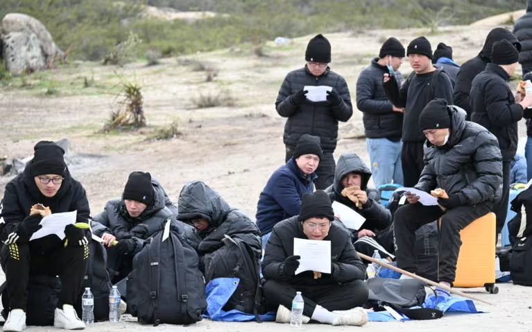 Những người nhập cư bất hợp pháp từ Trung Quốc đang cố gắng giữ ấm khi họ bị Lực lượng Tuần tra Biên giới Mỹ tạm giữ ở Nam California vào ngày 05/02, sau khi vượt biên từ Mexico. Ảnh: Masahiro Okoshi