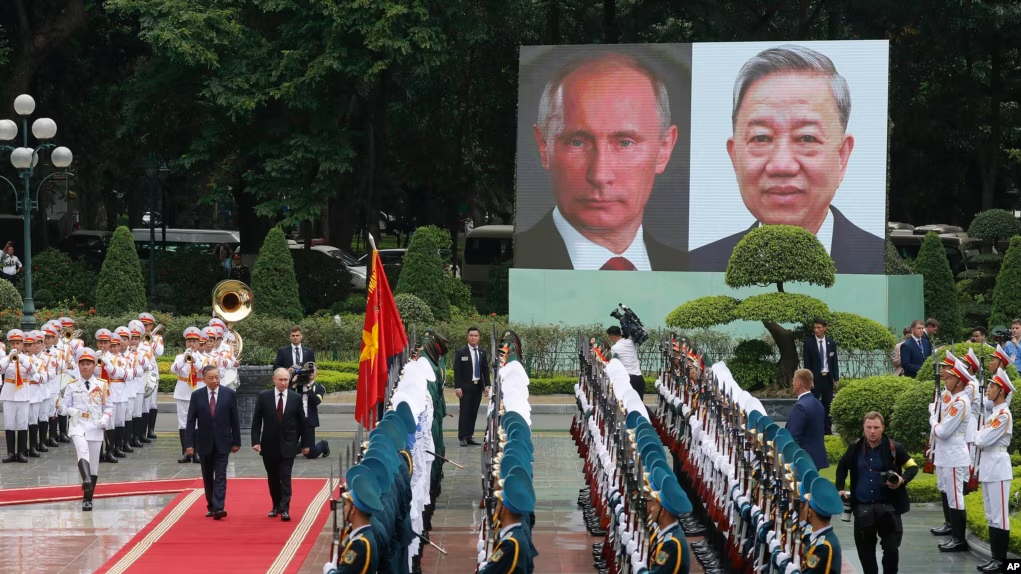 Ông Tô Lâm (phía trái trên thảm đỏ), và ông Putin, duyệt hàng quân danh dự tại Phủ Chủ Tịch tại Hà Nội, 20 tháng Sáu, 2024. Ảnh: AP