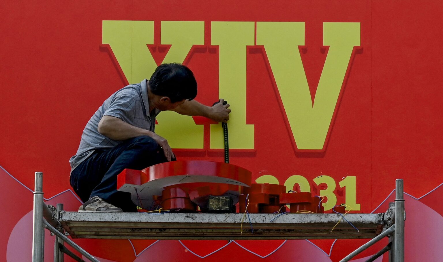 Một công nhân đang lắp đặt bảng quảng cáo cho đại hội 14 của đảng CSVN hôm 9 Tháng Giêng, 2026. Ảnh minh họa: Nhac Nguyen / AFP via Getty Images